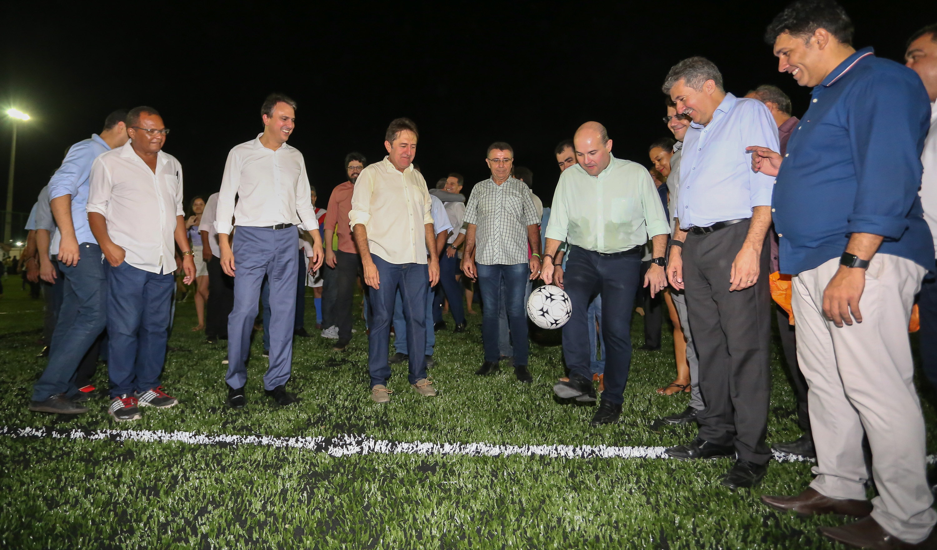 prefeito roberto cláudio chuta uma bola de futebol, cercado de várias pessoas